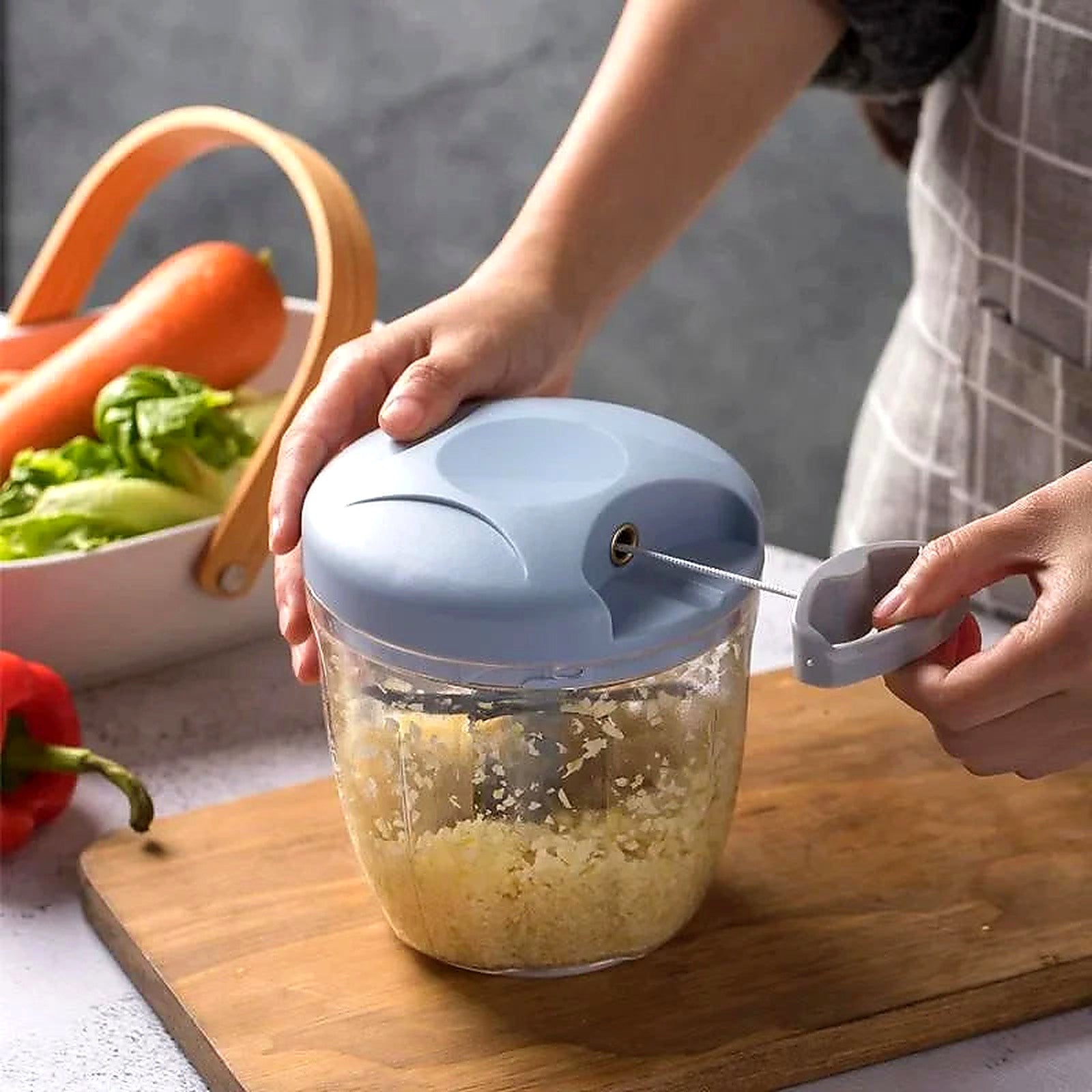 Hand using 12-in-1 manual chopper to mince garlic in kitchen — vegetable cutter in action
