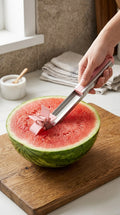 Hand pushing the windmill cutter into half a watermelon