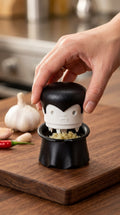 Hand pressing the Gracula vampire garlic crusher on a cutting board